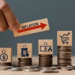 person using wood blocks and coins to show inflation of money, oil, and groceries